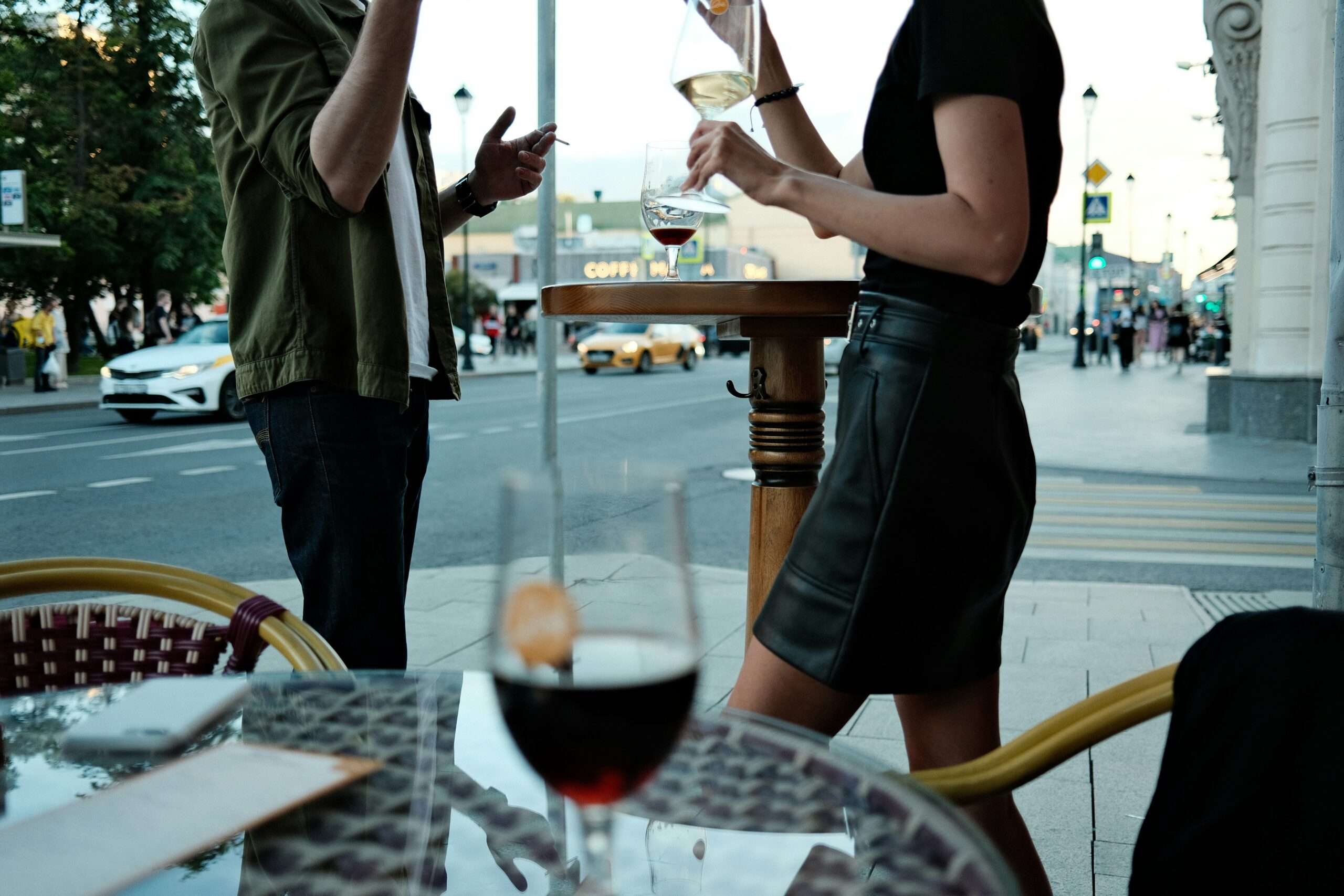 a man and a woman standing at a table with glasses of wine